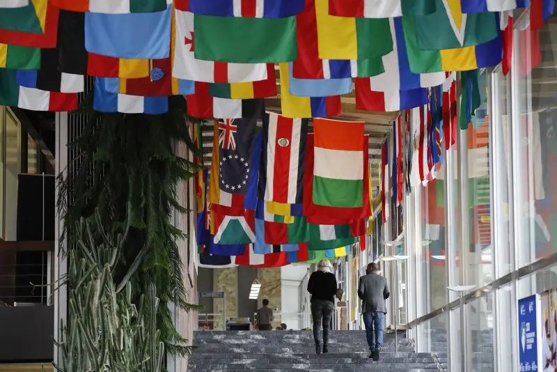 People walk down corridor with flags hanging from ceiling